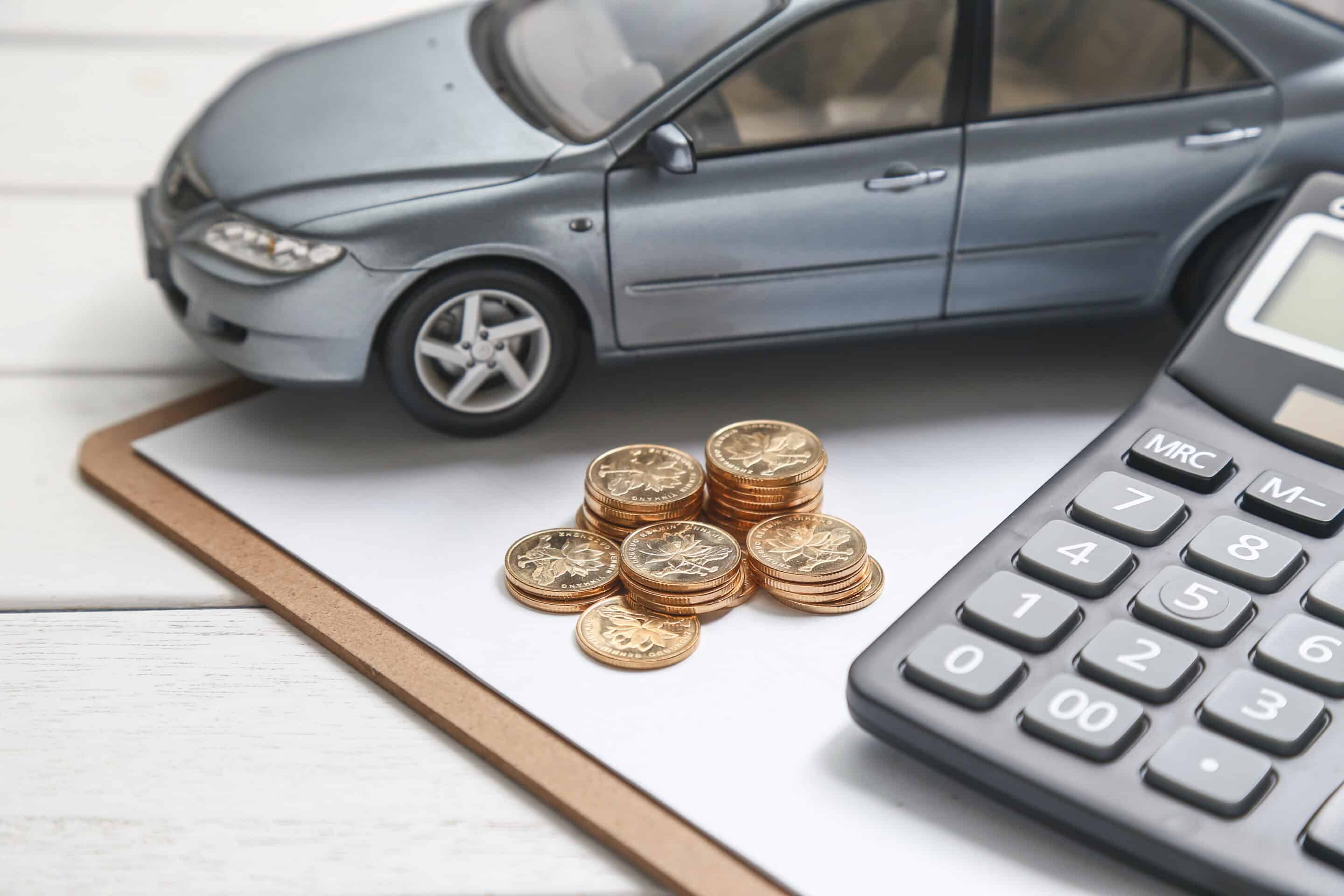 Miniatur-Fahrzeug, Taschenrechner und Münzen auf einem Notizbogen